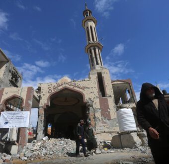 A man in black clothing walks past a mosque destroyed by airstrikes in Gaza.