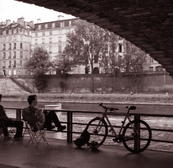 Two men look across a river at a European building.