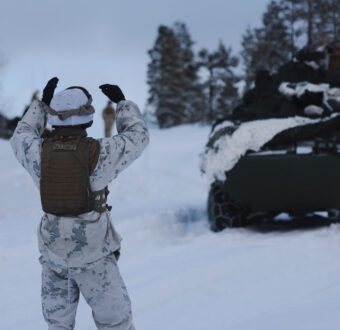 A US Marine gives hand and arm signals to a Light Armored Vehicle in Norway.